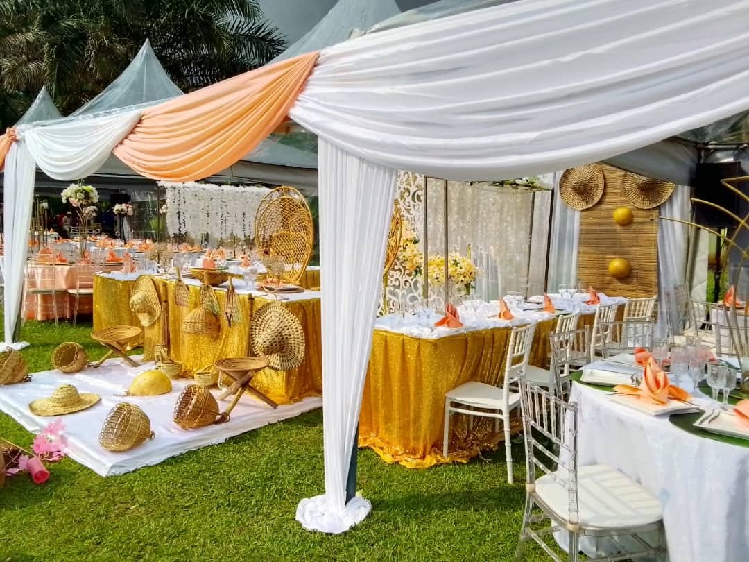Décor de cérémonie traditionnelle avec drapés corail, or et vannerie camerounaise