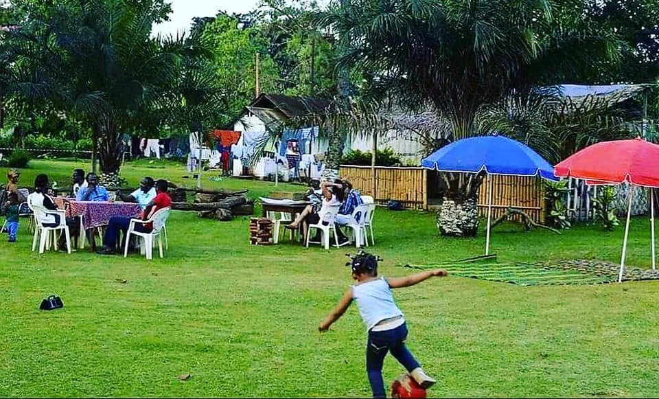 Loisirs en plein air au Clos des Roses — Familles attablées sous des parasols pendant qu'un enfant joue au ballon