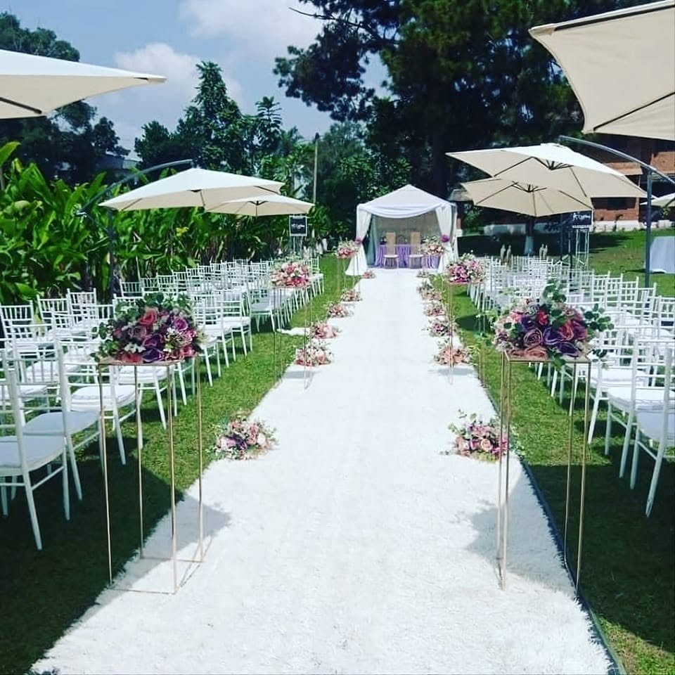 Allée de mariage blanche bordée de chaises et de parasols, compositions florales violettes