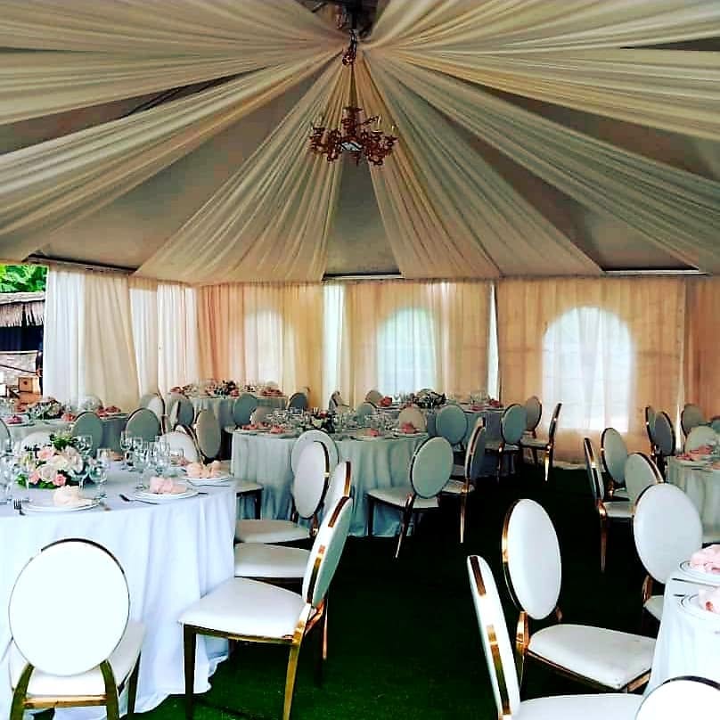 Intérieur de tente aux drapés ivoire avec lustre et tables dressées