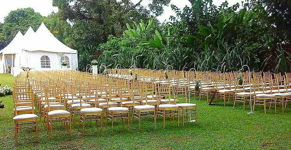 Grand rassemblement en plein air : chaises dorées alignées et tente blanche