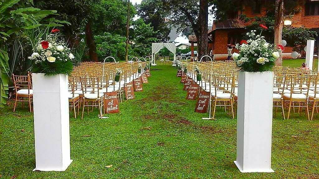 Allée de cérémonie fleurie et chaises dorées installées sur la pelouse