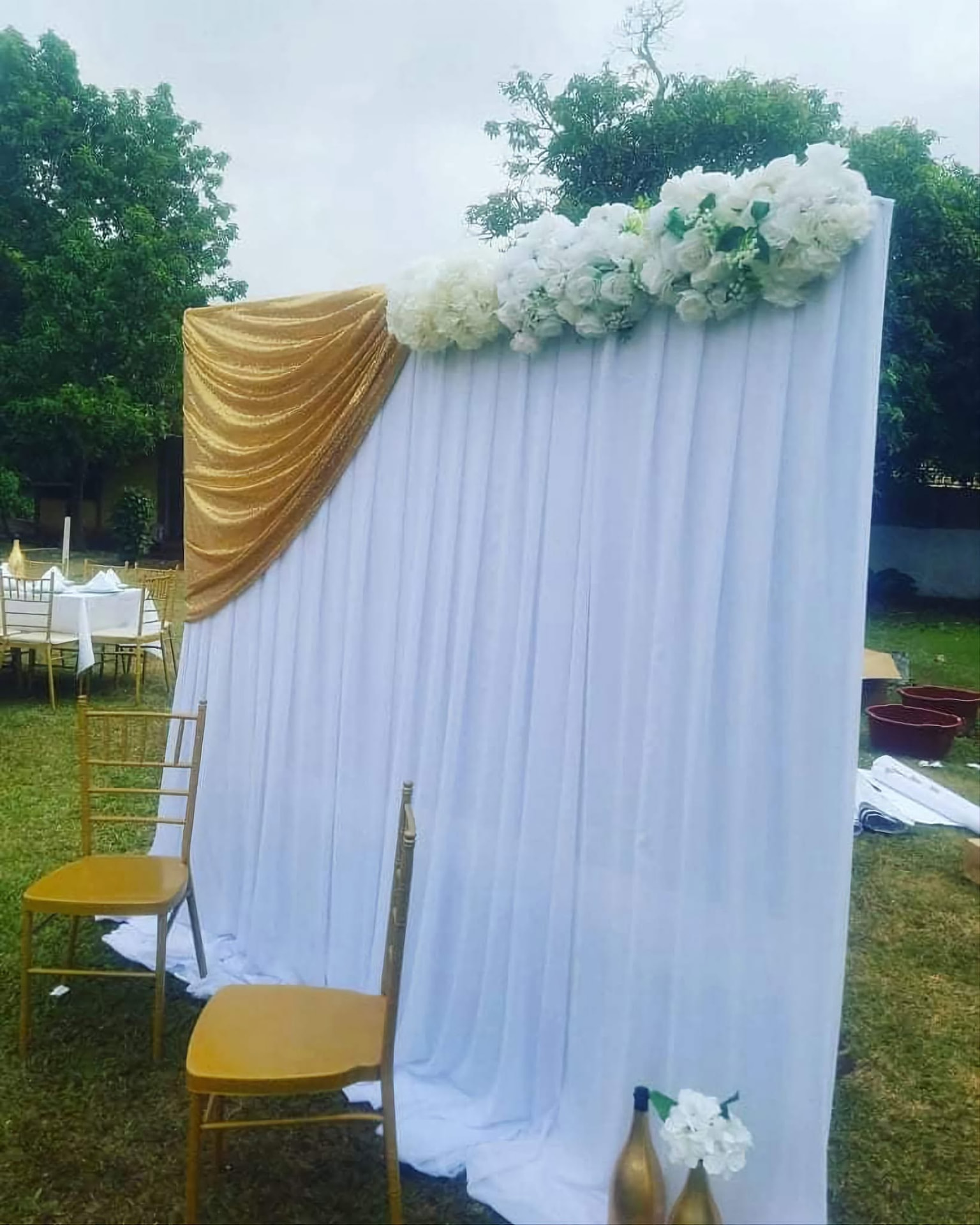 Photocall blanc drapé d'or et de fleurs blanches dans le jardin