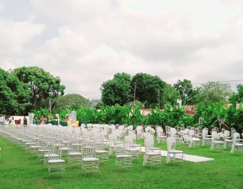 Cérémonie en plein air avec rangées de chaises blanches entourées de verdure