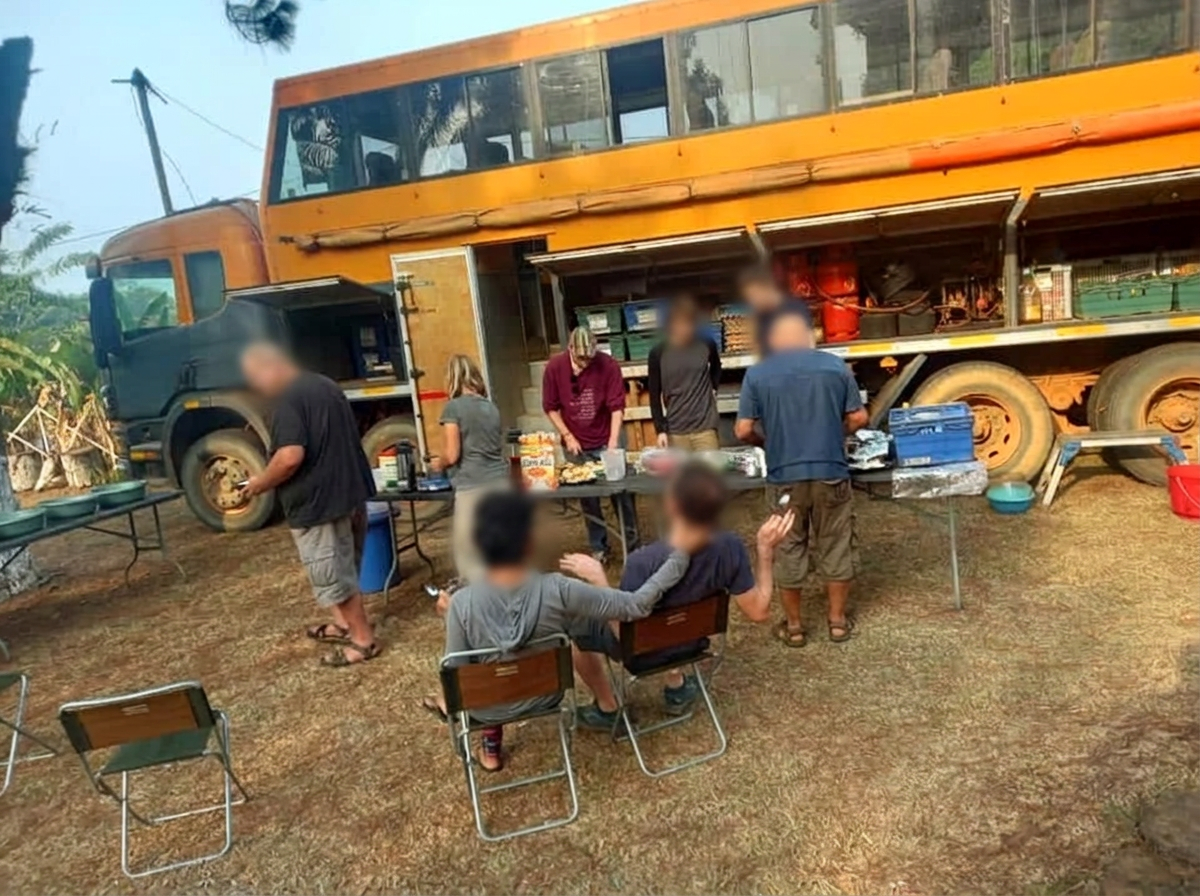 Groupe de voyageurs préparant un repas près de leur camion aménagé